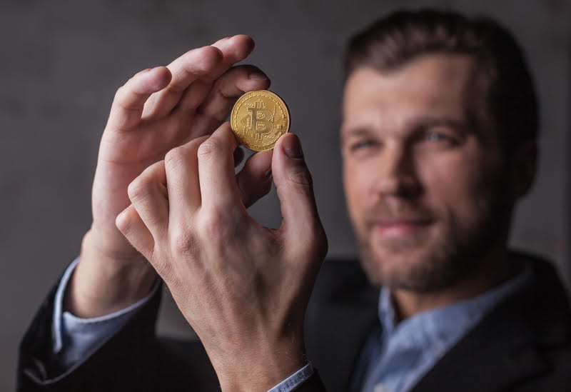 A man holding a gold coin, representing cryptocurrencies as the new gold in the investment landscape