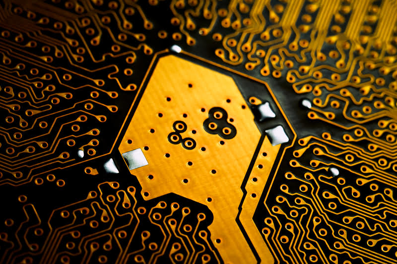 A circuit board with yellow and black components, highlighting gold's use in technology