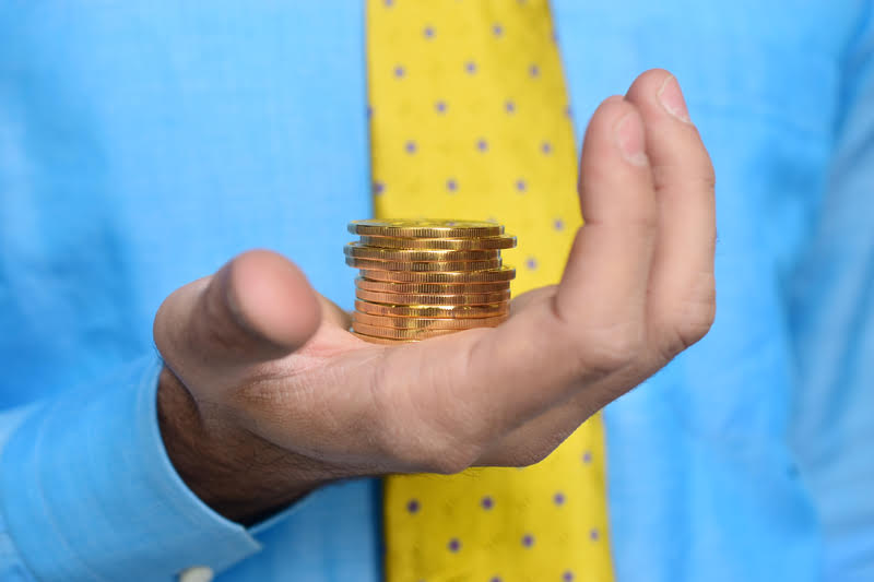 A man holding a stack of gleaming gold coins, symbolizing the enduring allure of gold throughout history